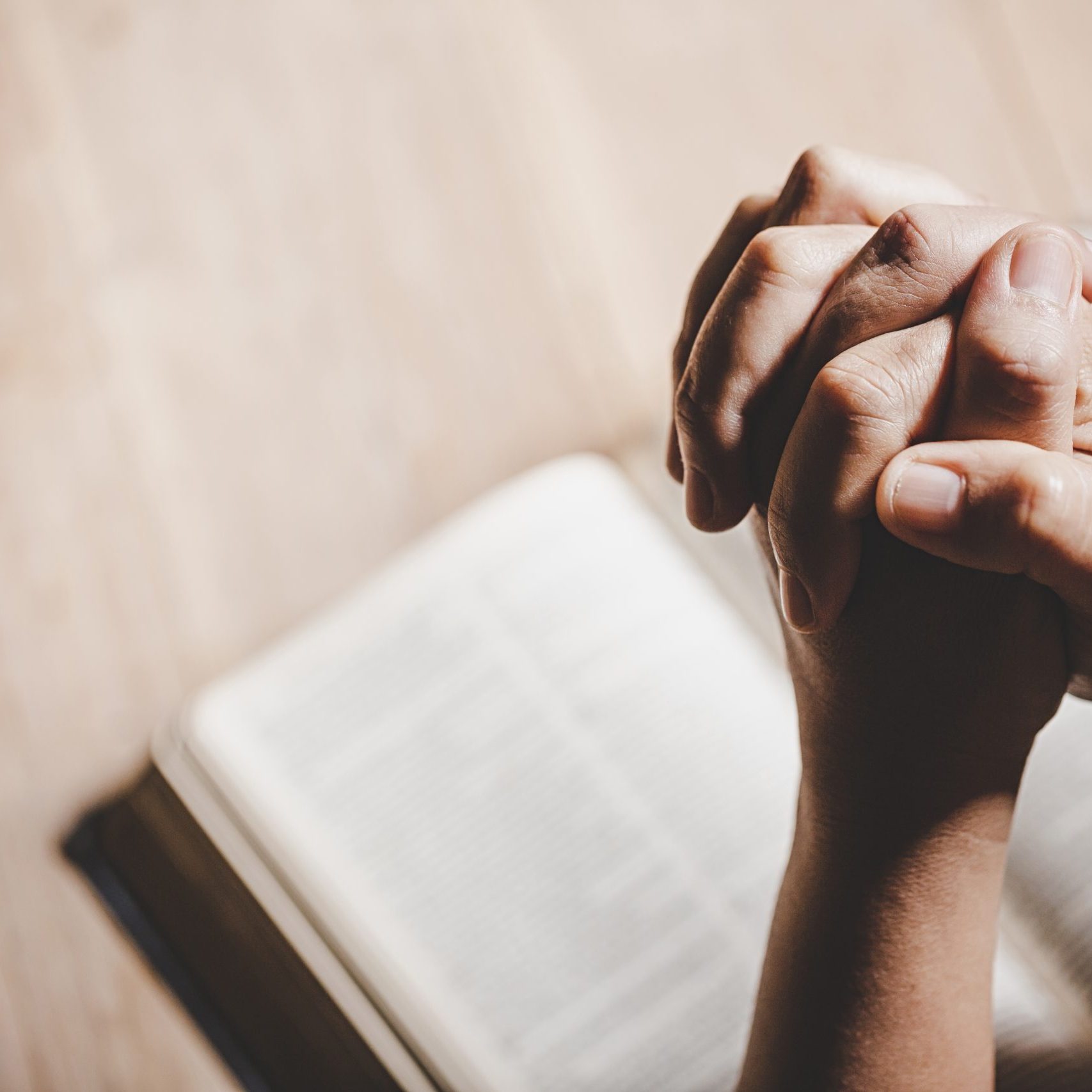 Spirituality and religion, Hands folded in prayer on a Holy Bible in church concept for faith.